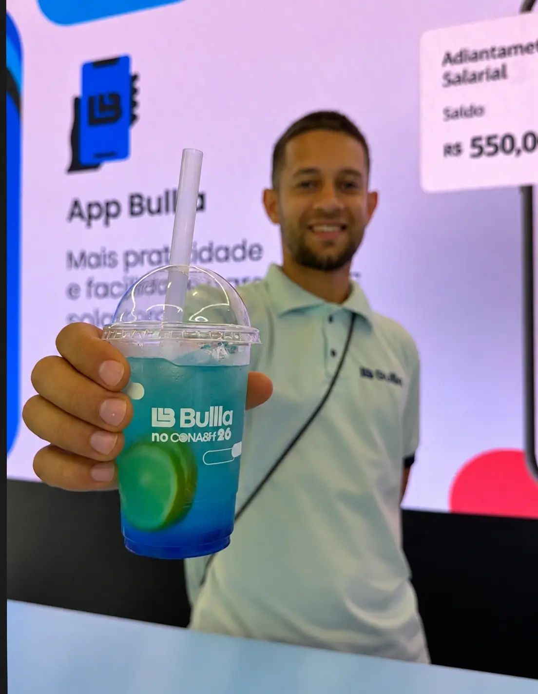 Atendente sorrindo ao servir drink gelado azul em copo personalizado da marca Bulla em evento corporativo.
